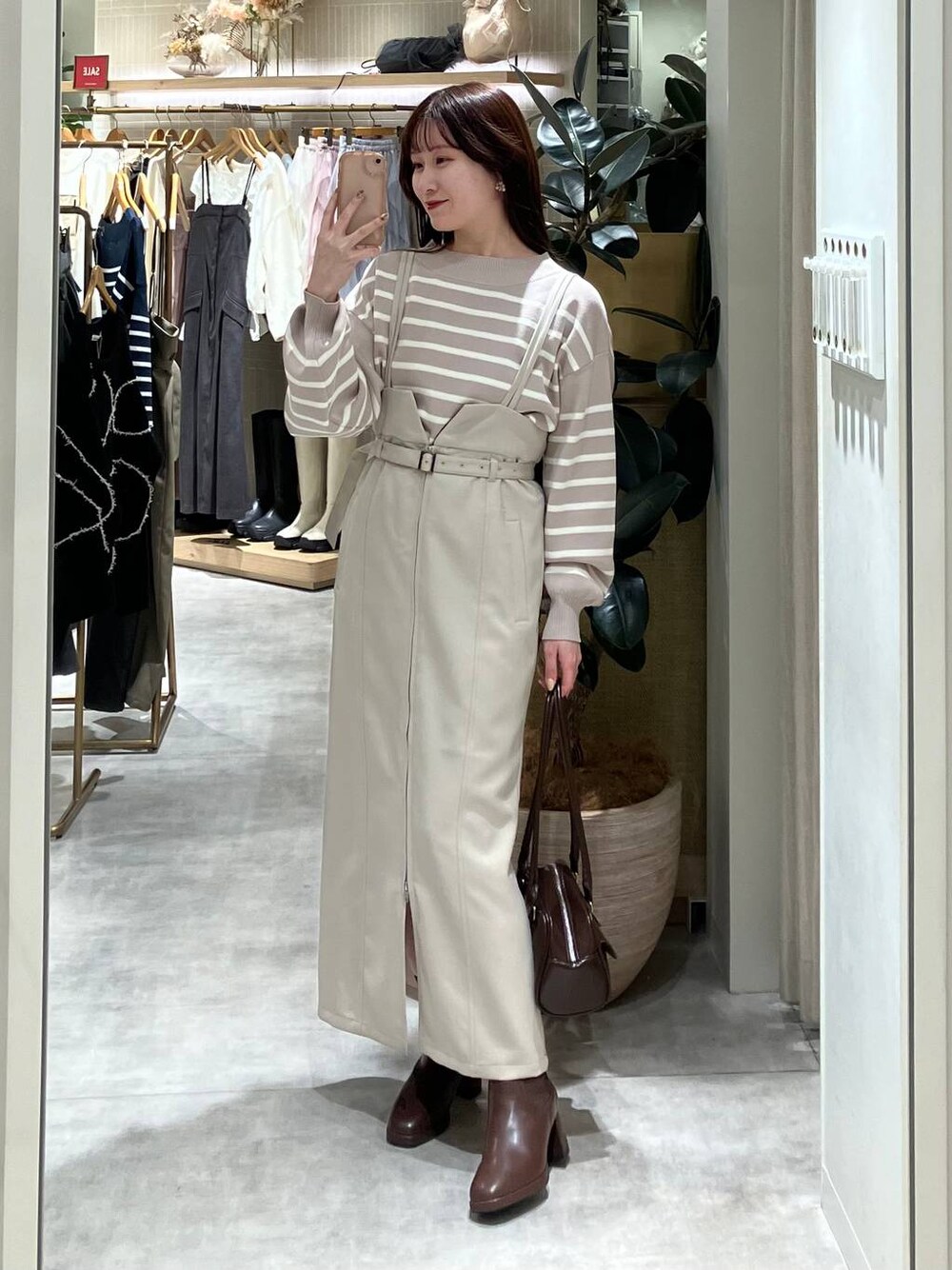 ブラウン系のブーツ、ブラウン系のハンドバッグ、ベージュ系のニット/セーターを着用したレディースの冬コーディネートの1枚目の写真