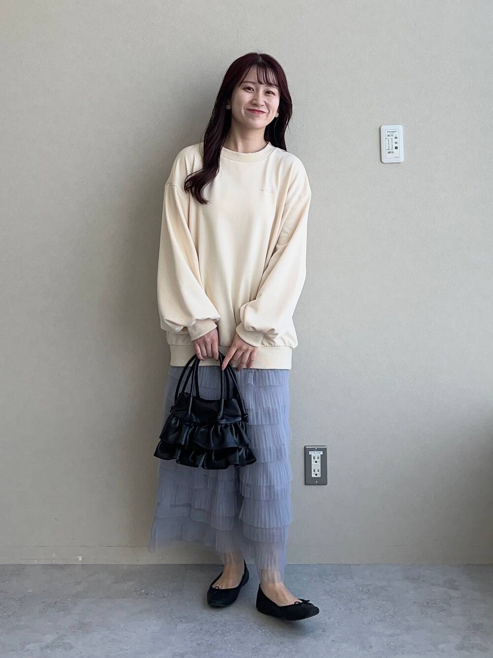 ブラック系のショルダーバッグ、ホワイト系のスウェット、グレー系のスカートを着用したレディースの冬コーディネートの1枚目の写真