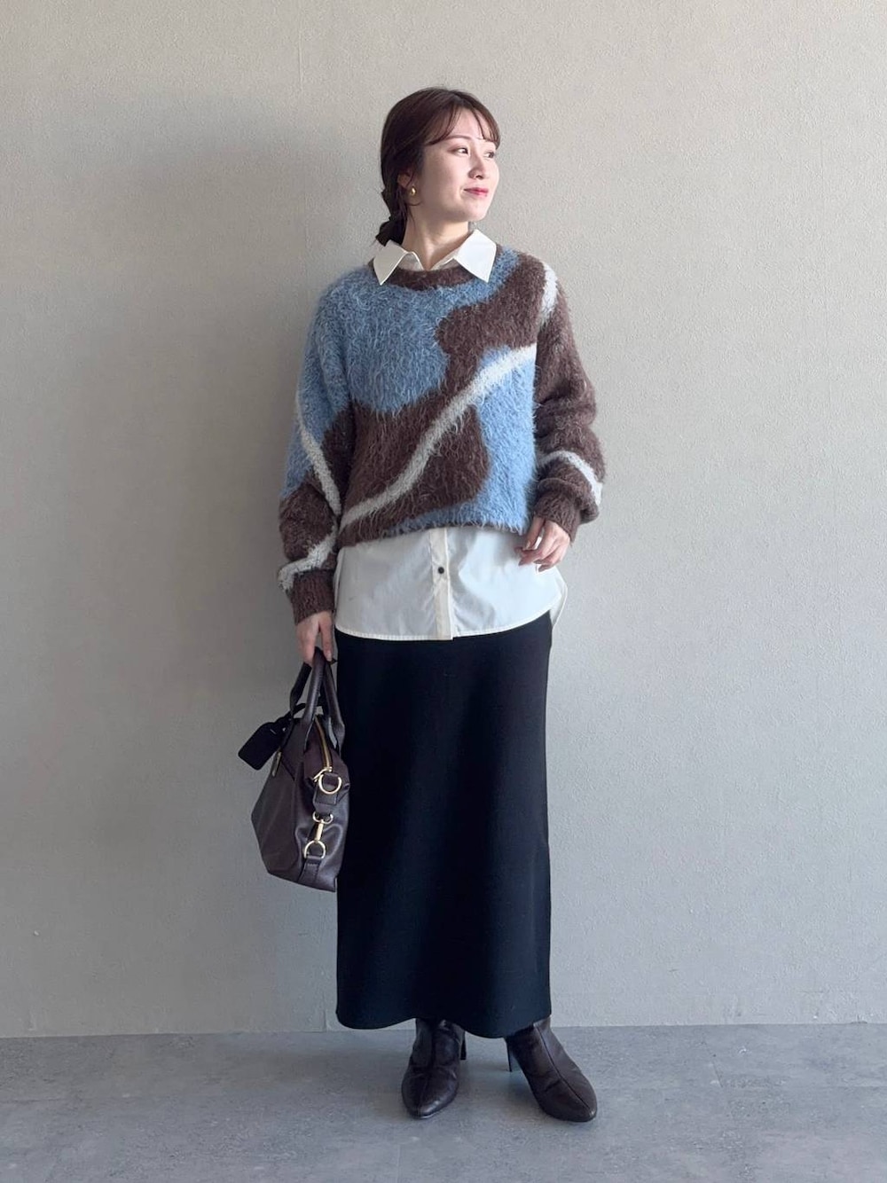 ブラウン系のニット/セーター、ブラウン系のボストンバッグ、ブラック系のスカートを着用したレディースの冬コーディネートの1枚目の写真