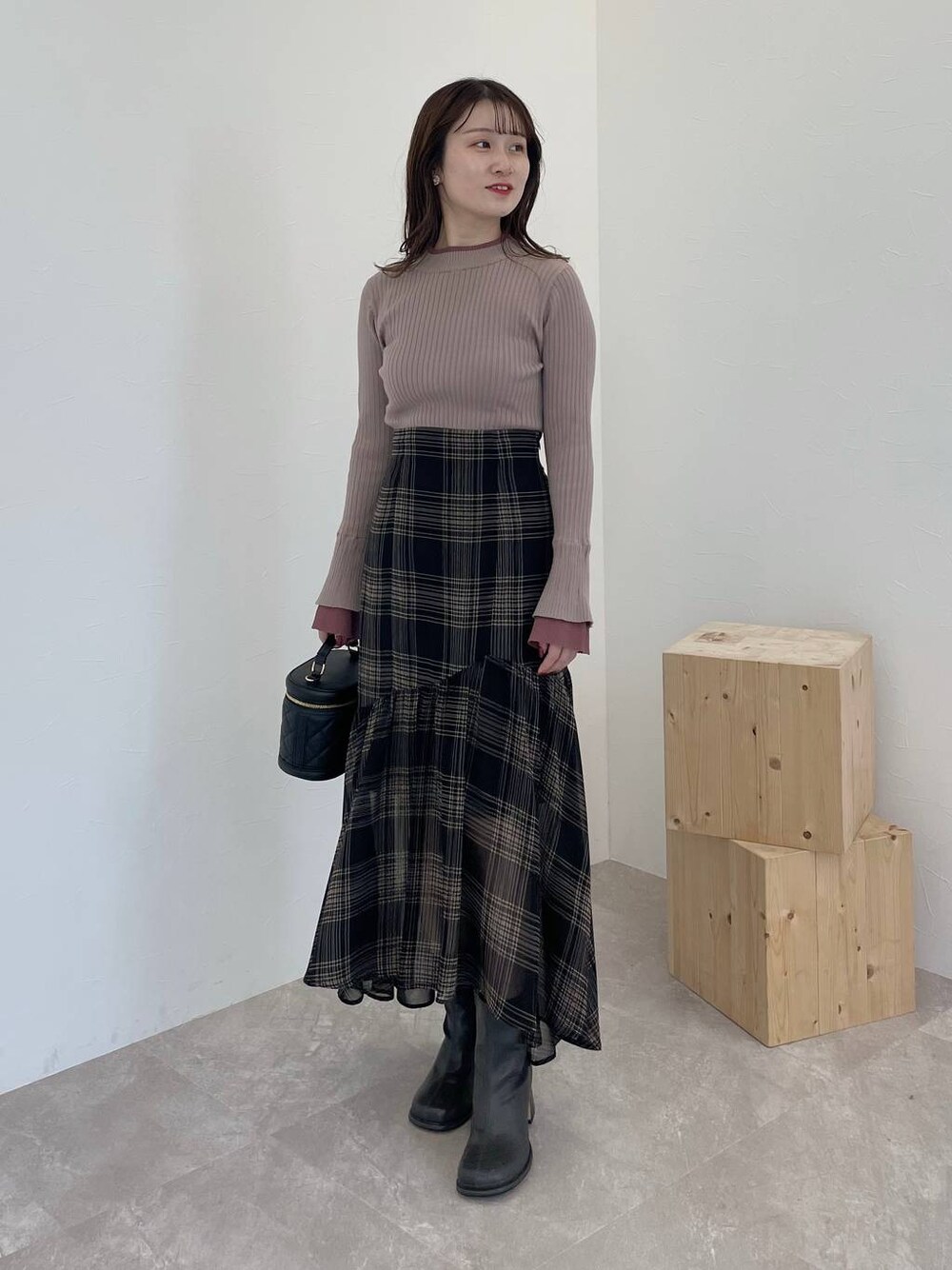 グレー系のブーツ、ブラック系のショルダーバッグ、ブラウン系のニット/セーターを着用したレディースの秋コーディネートの1枚目の写真