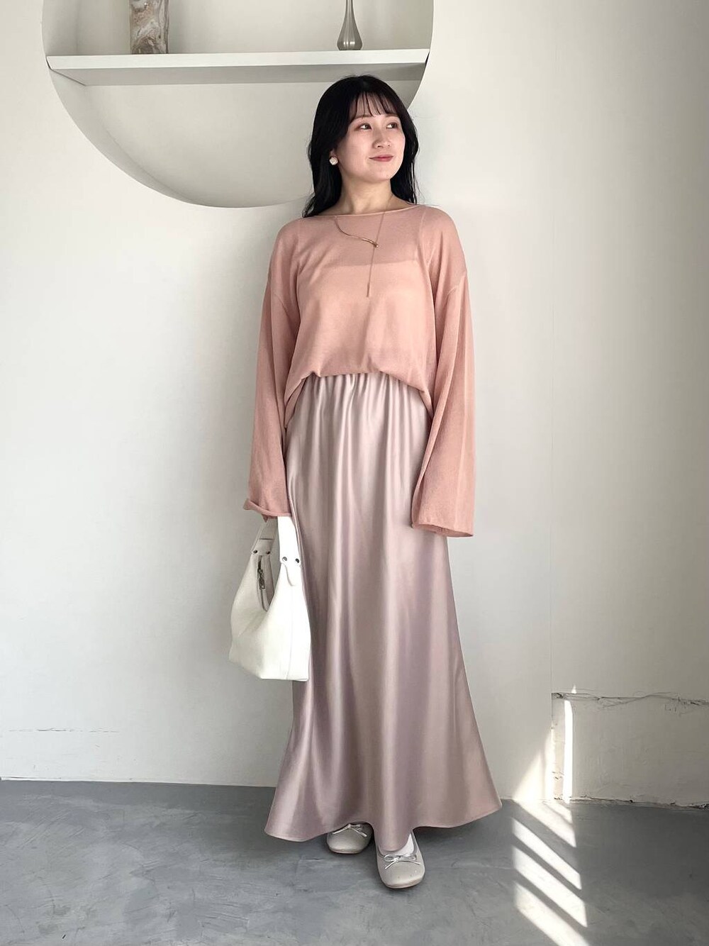 ピンク系のニット/セーター、シルバー系のバレエシューズ、ホワイト系のキャミソールを着用したレディースの春コーディネートの1枚目の写真