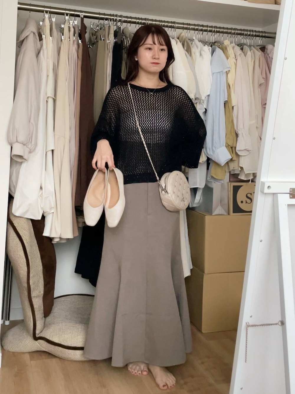 ブラック系のニット/セーター、ベージュ系のスカートを着用したレディースの夏コーディネートの1枚目の写真