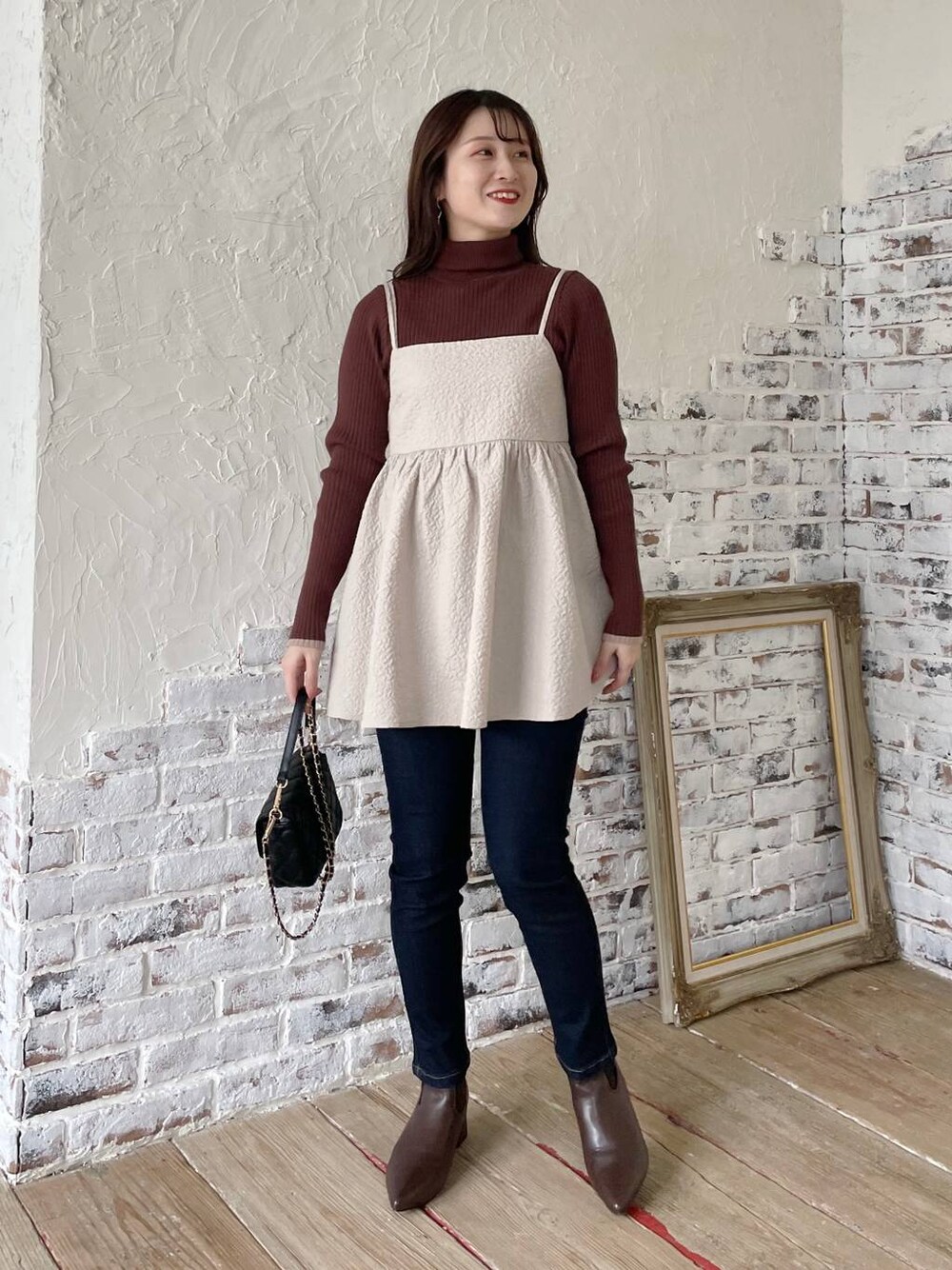 ブルー系のデニムパンツ、ベージュ系のキャミソール、ブラウン系のニット/セーターを着用したレディースの冬コーディネートの1枚目の写真