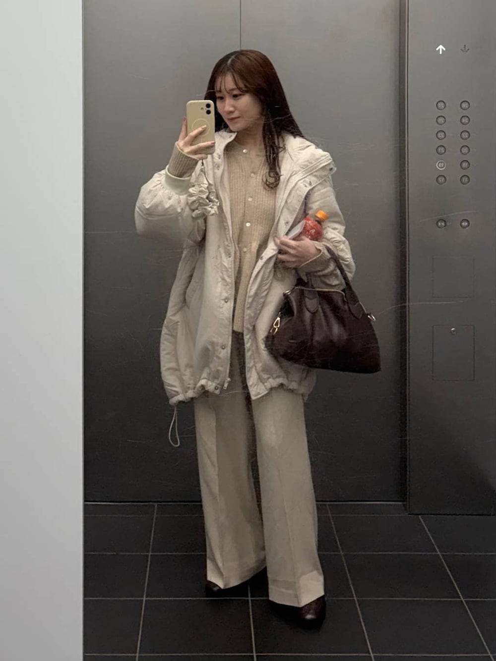 ブラウン系のボストンバッグ、ホワイト系のスラックス、ベージュ系のカーディガン/ボレロを着用したレディースの冬コーディネートの1枚目の写真