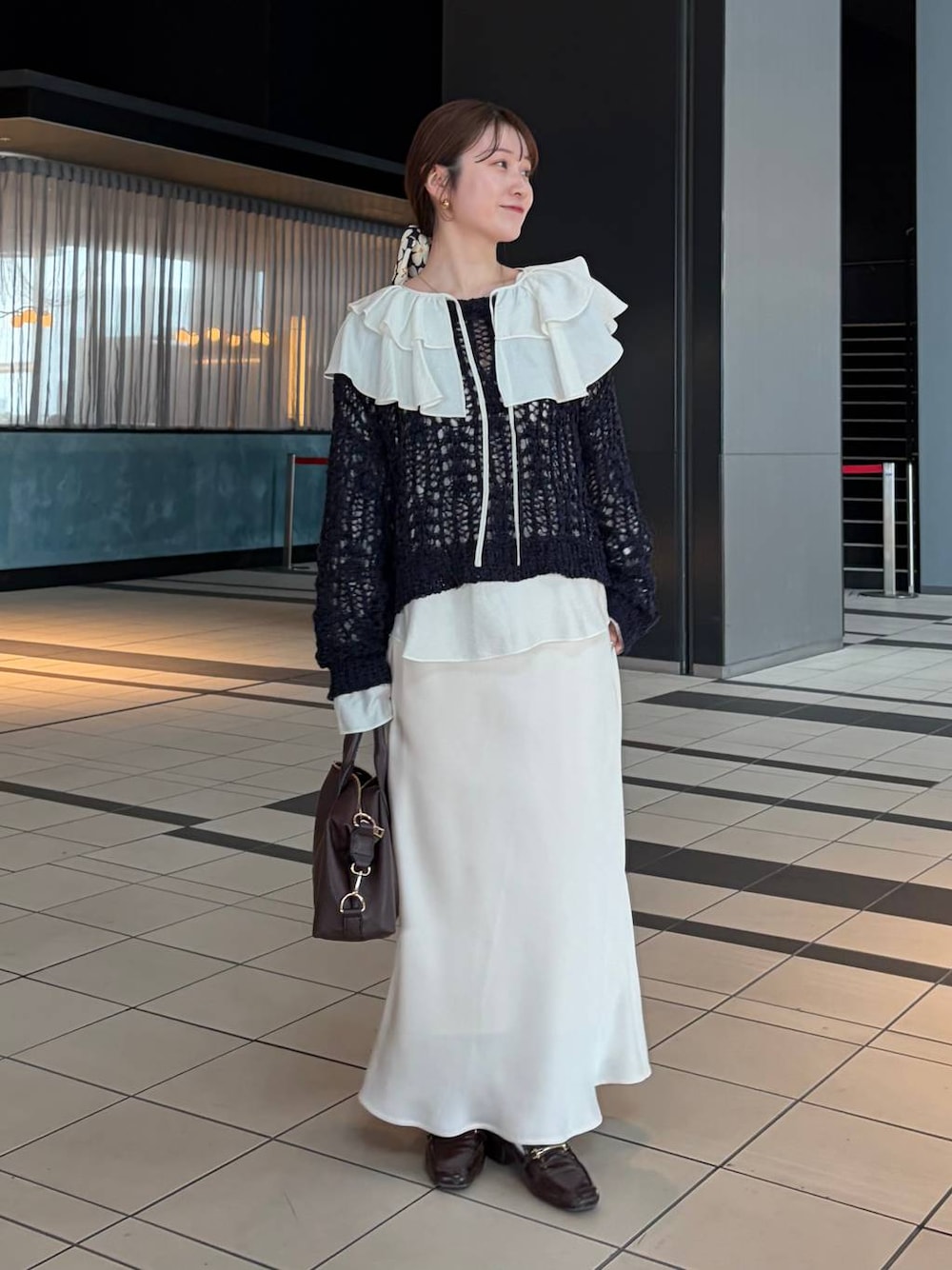 ブラウン系のボストンバッグ、ホワイト系のシャツ/ブラウス、ブルー系のニット/セーターを着用したレディースの冬コーディネートの1枚目の写真