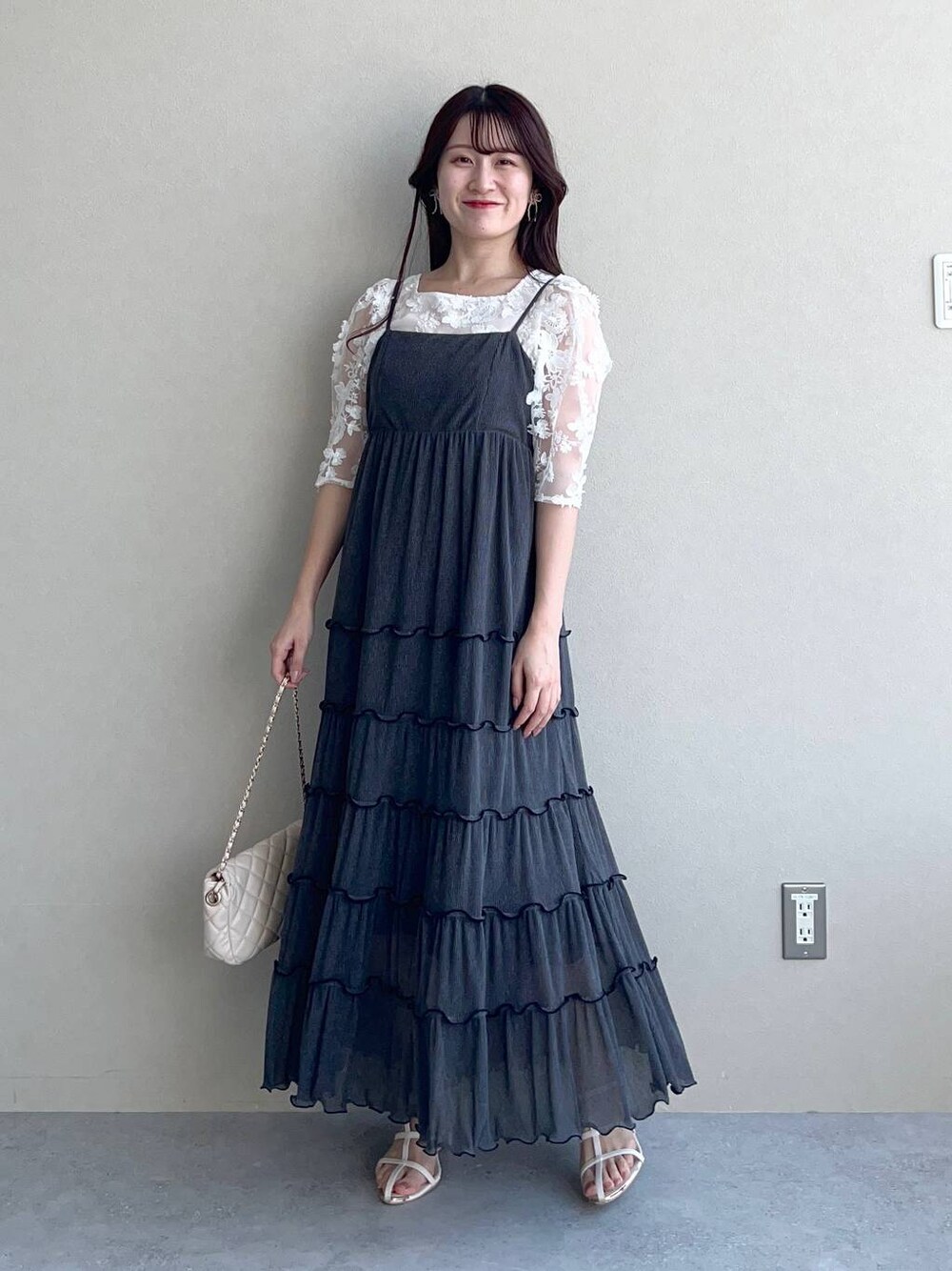 グレー系のワンピース、ホワイト系のショルダーバッグ、ホワイト系のサンダルを着用したレディースの夏コーディネートの1枚目の写真