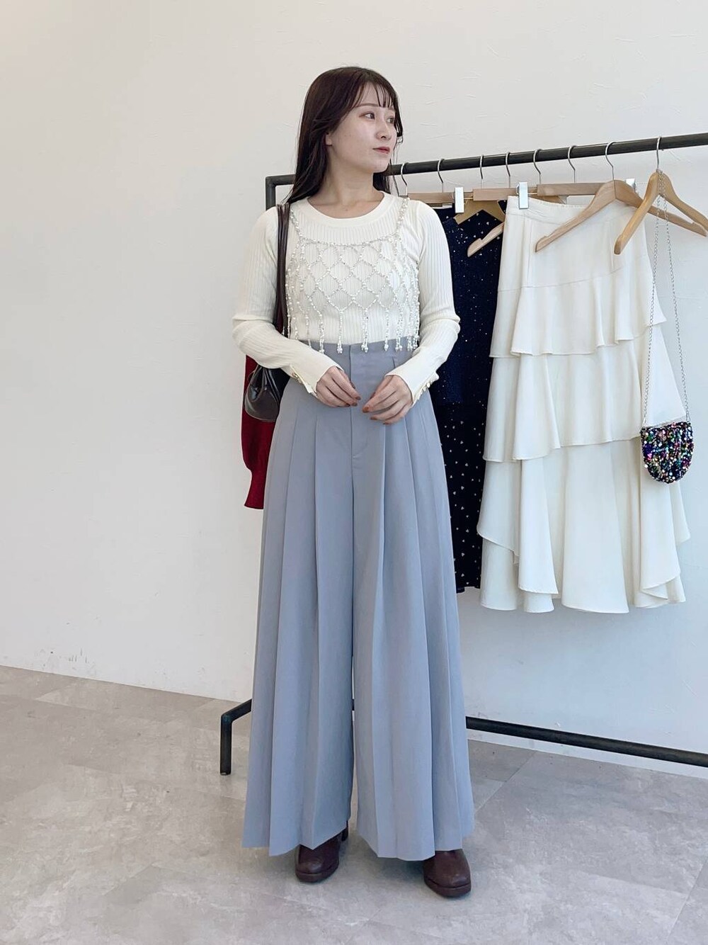 ブラウン系のブーツ、ホワイト系のニット/セーター、ブラウン系のハンドバッグを着用したレディースの冬コーディネートの1枚目の写真