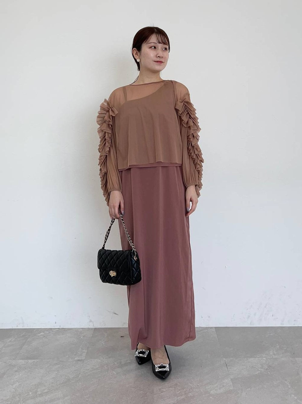 ブラック系のパンプス、ピンク系のドレス、ブラック系のショルダーバッグを着用したレディースの夏コーディネートの1枚目の写真