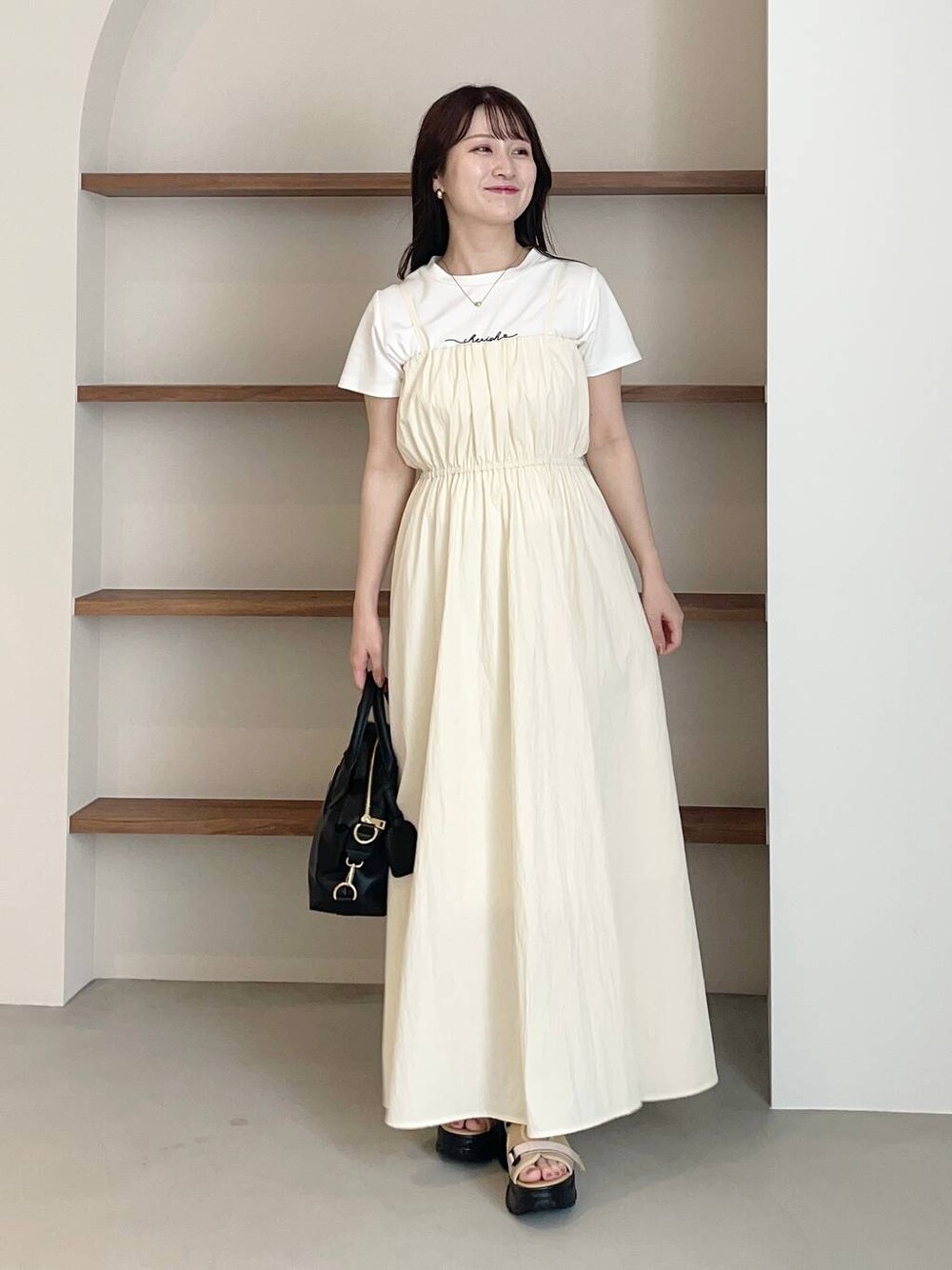 ベージュ系のサンダル、ホワイト系のTシャツ/カットソー、ブラック系のボストンバッグを着用したレディースの夏コーディネートの1枚目の写真