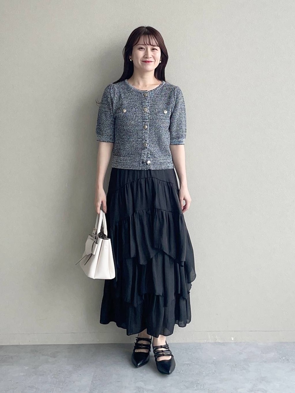 ホワイト系のショルダーバッグ、ブラック系のパンプス、ブラック系のカーディガン/ボレロを着用したレディースの夏コーディネートの1枚目の写真