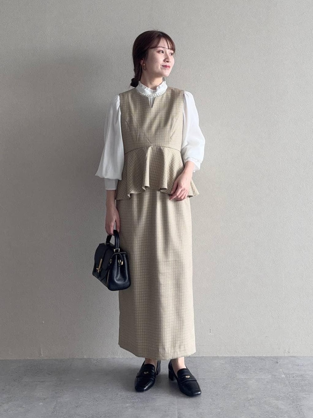 ブラック系のローファー、ブラック系のショルダーバッグ、ベージュ系のワンピースを着用したレディースの冬コーディネートの1枚目の写真