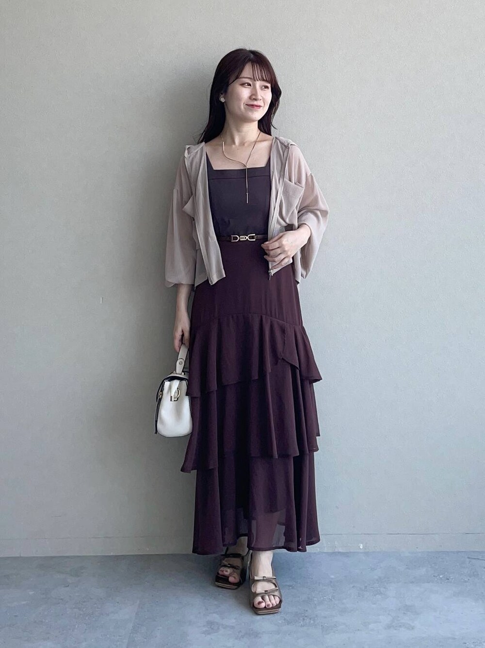 ベージュ系のパーカー、ブラウン系のサンダル、ホワイト系のショルダーバッグを着用したレディースの夏コーディネートの1枚目の写真