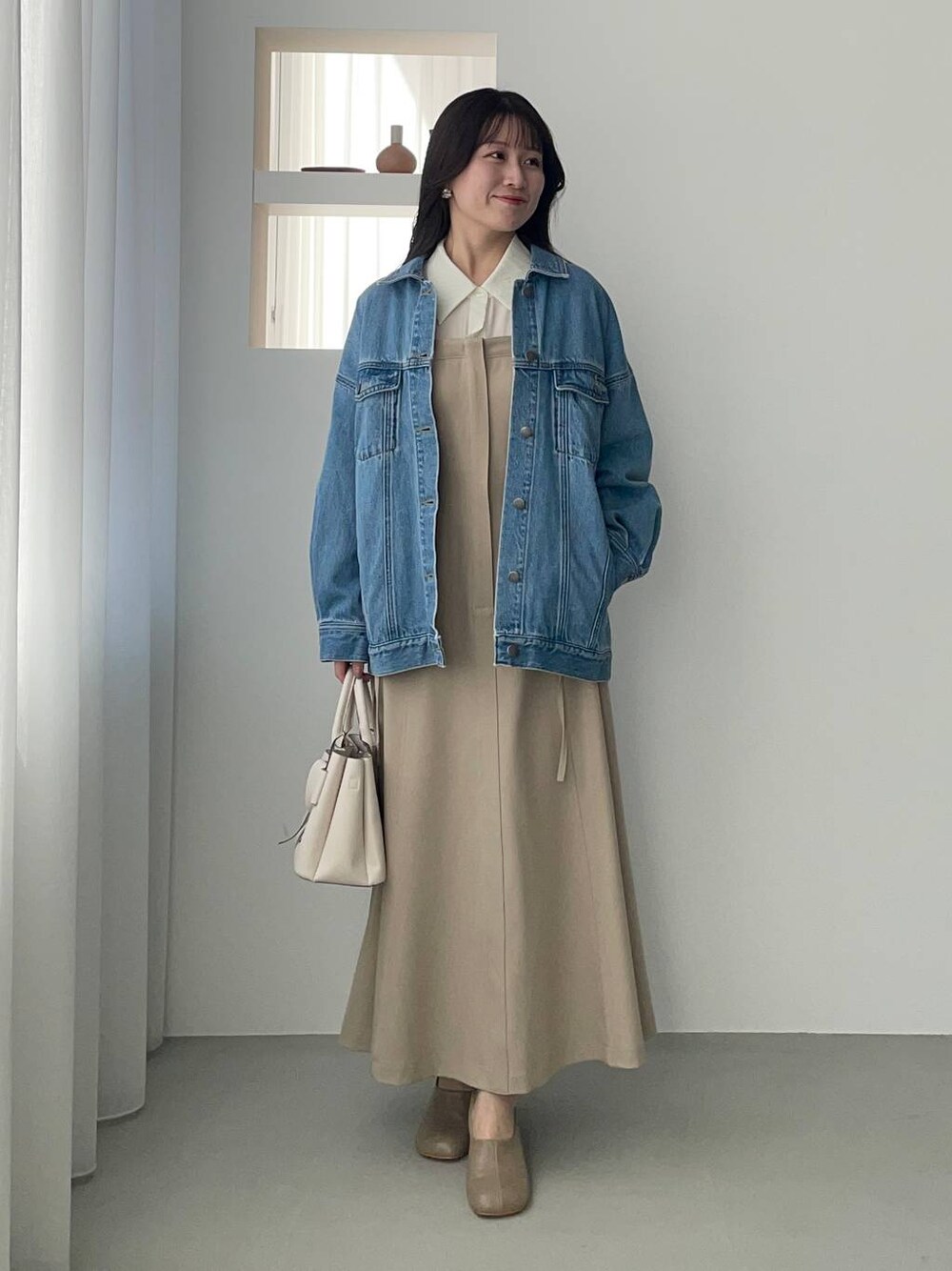 ブルー系のデニムジャケット、ホワイト系のショルダーバッグ、ブラウン系のパンプスを着用したレディースの冬コーディネートの1枚目の写真