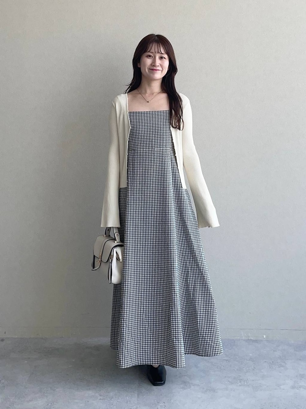 ホワイト系のショルダーバッグ、ブラック系のワンピース、ホワイト系のカーディガン/ボレロを着用したレディースの夏コーディネートの1枚目の写真