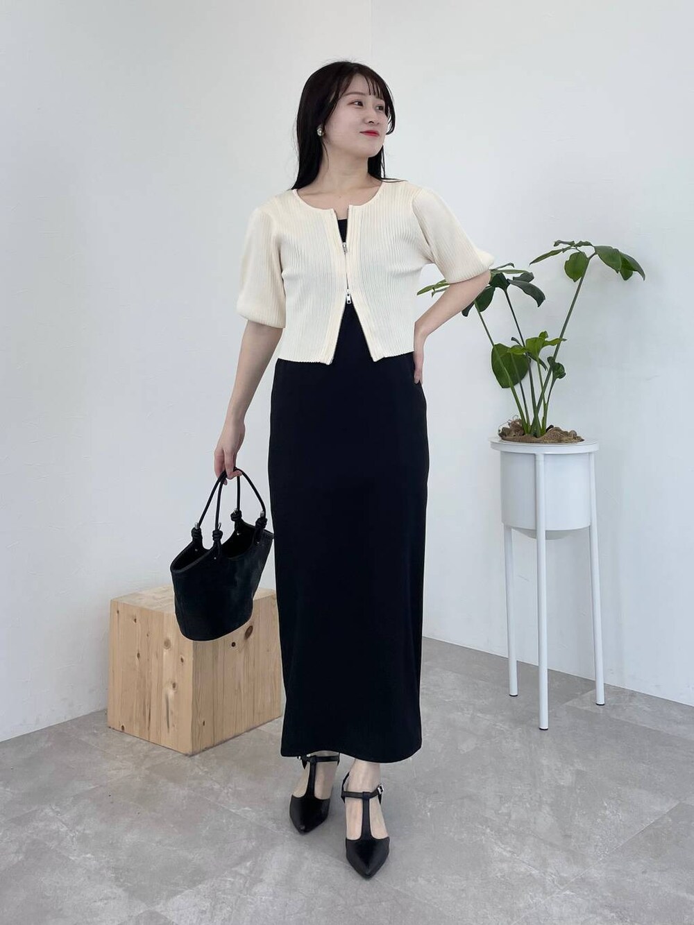 ブラック系のドレス、ブラック系のハンドバッグ、ブラック系のパンプスを着用したレディースの春コーディネートの1枚目の写真