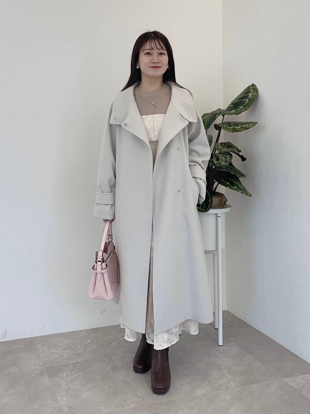 ホワイト系のチェスターコート、ピンク系のショルダーバッグ、ブラウン系のブーツを着用したレディースの冬コーディネートの1枚目の写真