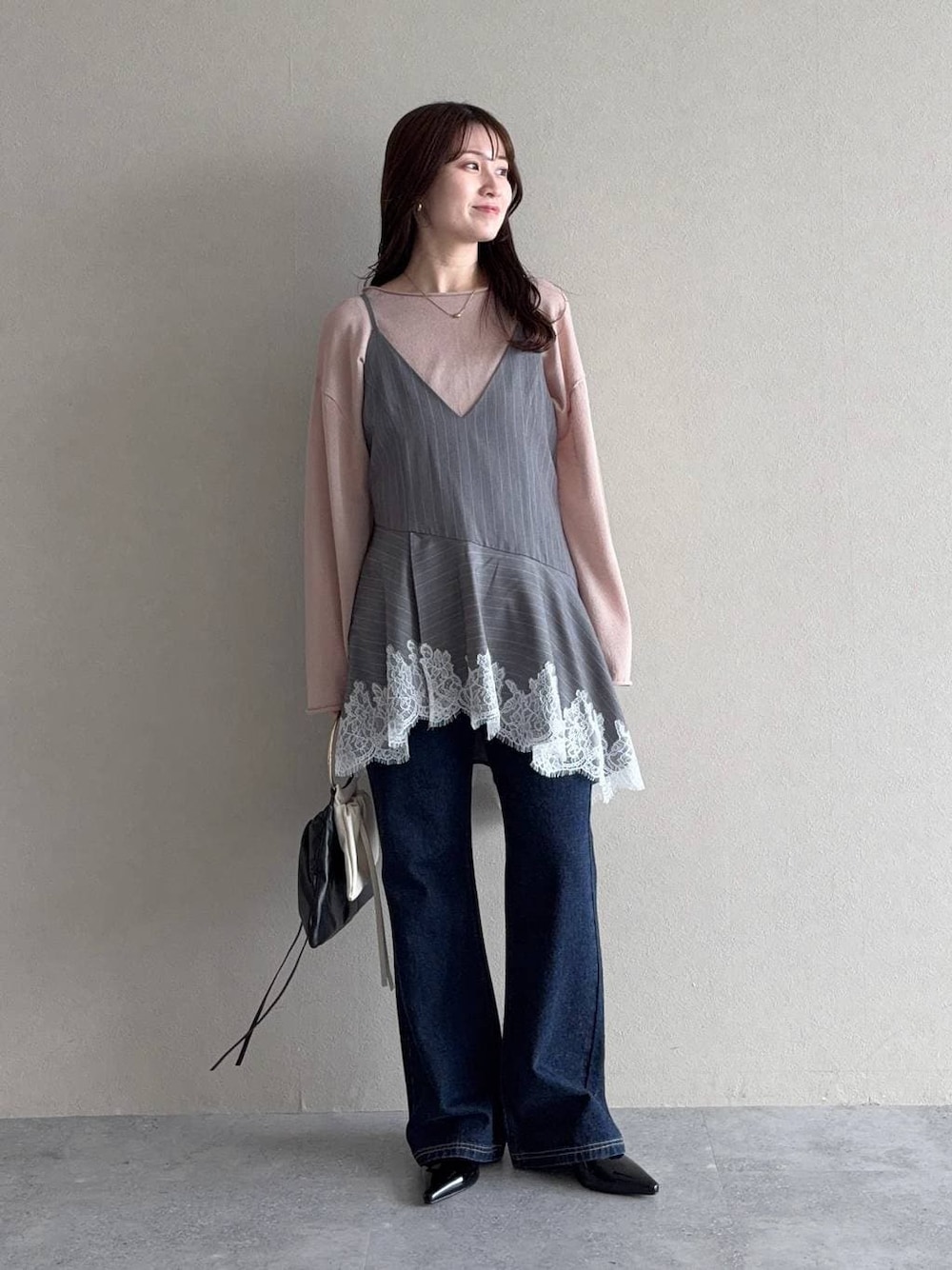 ベージュ系のニット/セーター、ブルー系のデニムパンツ、ブラック系のサンダルを着用したレディースの春コーディネートの1枚目の写真