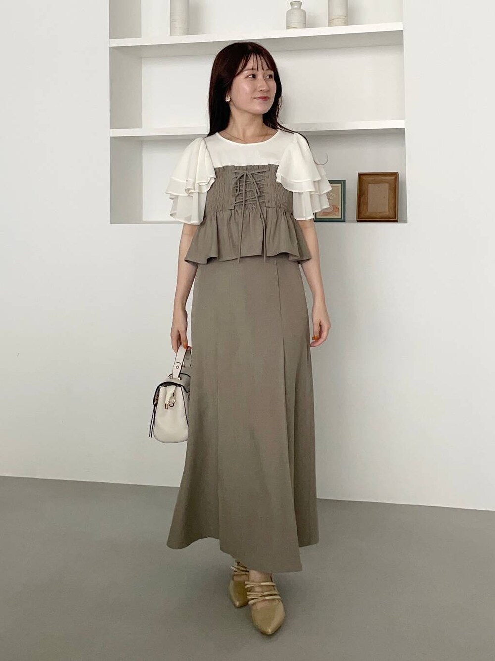 ゴールド系のパンプス、ホワイト系のショルダーバッグ、ホワイト系のTシャツ/カットソーを着用したレディースの春コーディネートの1枚目の写真