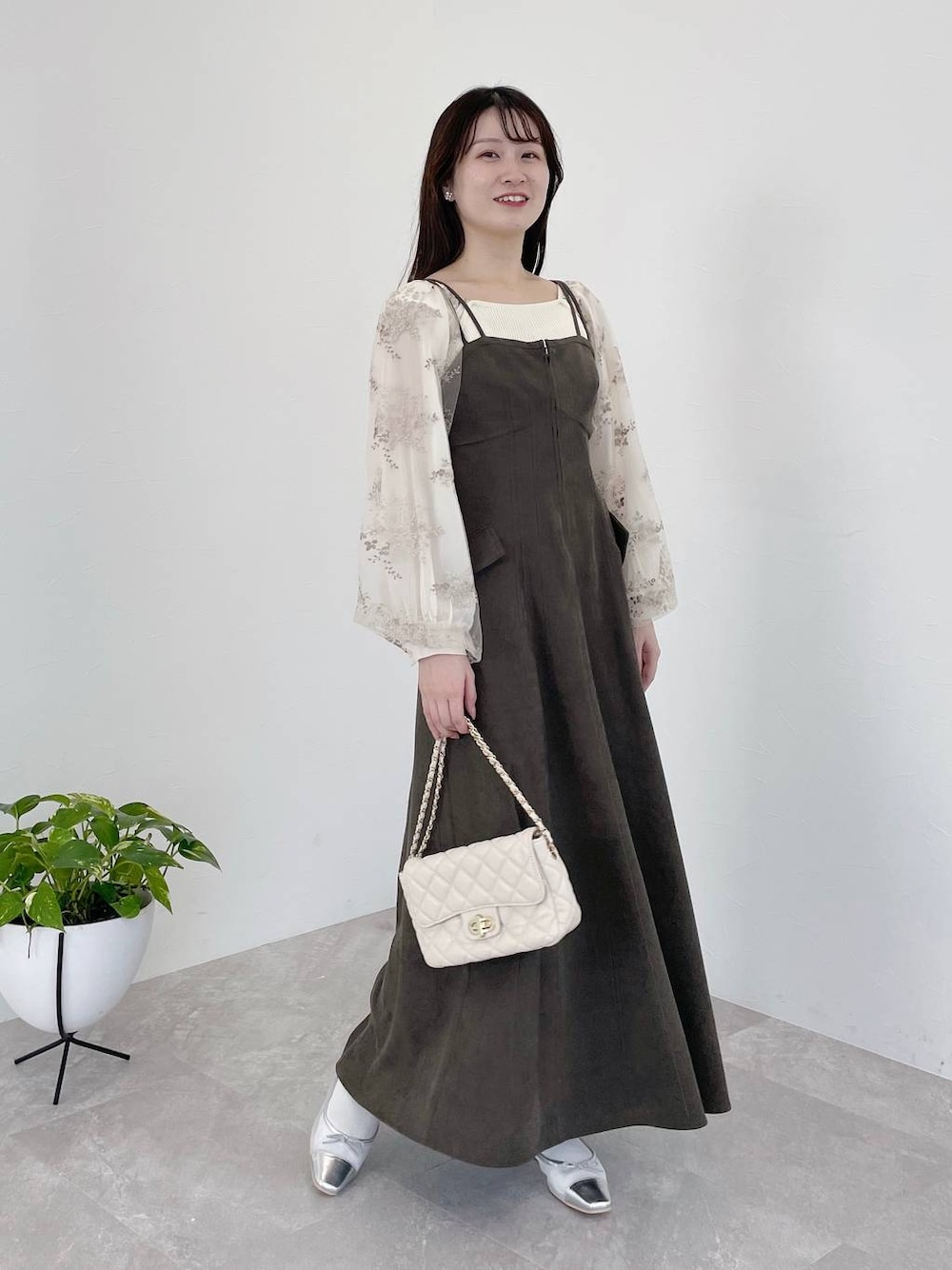 グレー系のワンピース、ホワイト系のショルダーバッグ、ホワイト系のニット/セーターを着用したレディースの冬コーディネートの1枚目の写真