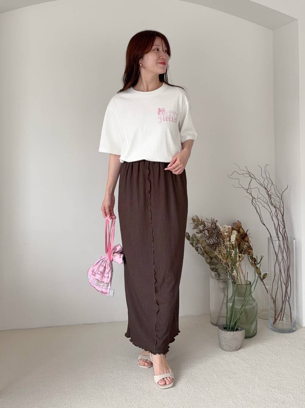 ブラウン系のスカート、ホワイト系のTシャツ/カットソー、ホワイト系のサンダルを着用したレディースの夏コーディネートの1枚目の写真