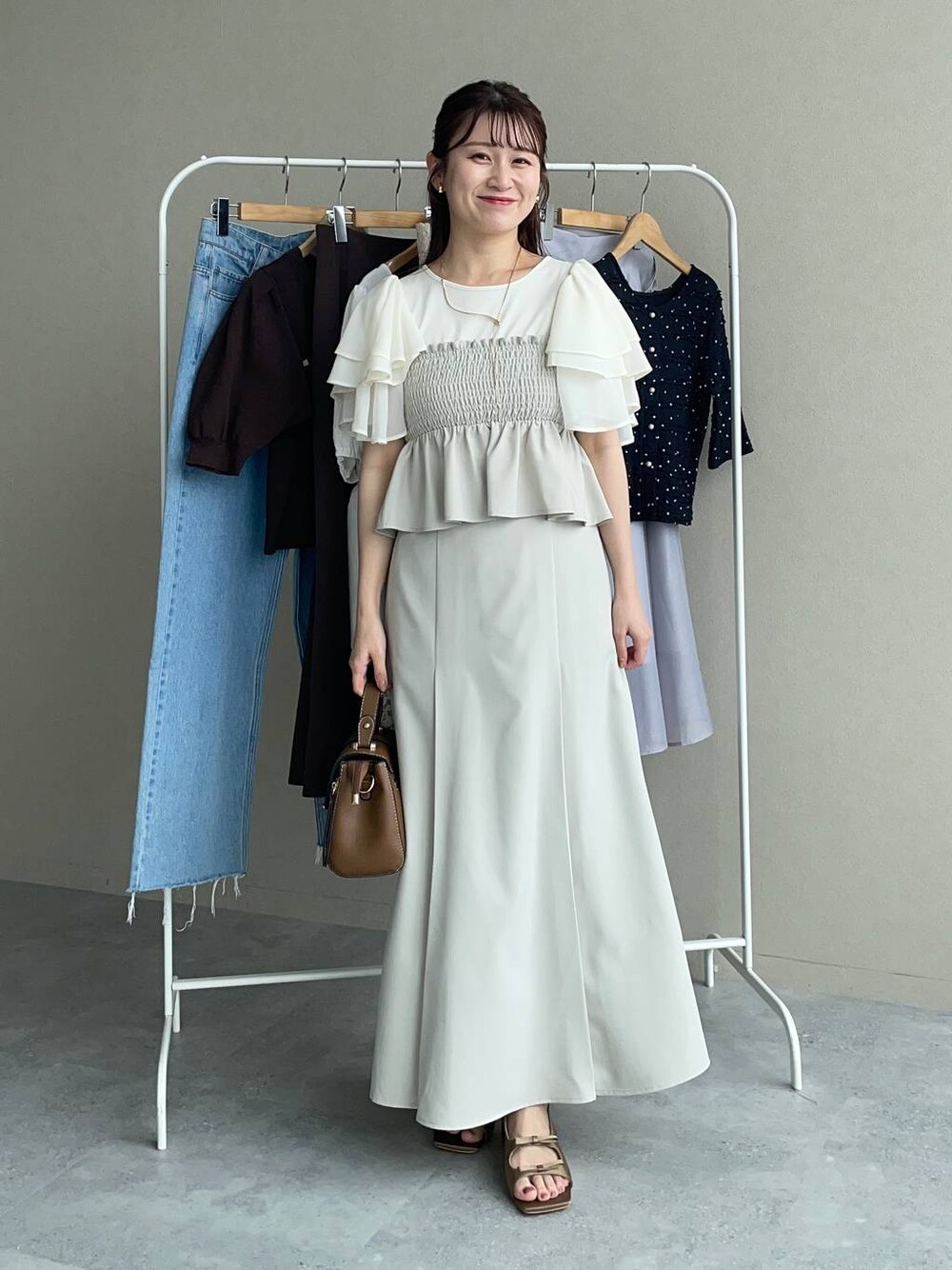 ブラウン系のサンダル、ブラウン系のショルダーバッグ、ホワイト系のTシャツ/カットソーを着用したレディースの夏コーディネートの1枚目の写真