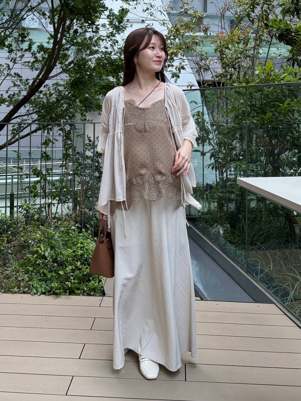 ベージュ系のキャミソール、ベージュ系のスカート、ブラウン系のショルダーバッグを着用したレディースの夏コーディネートの1枚目の写真
