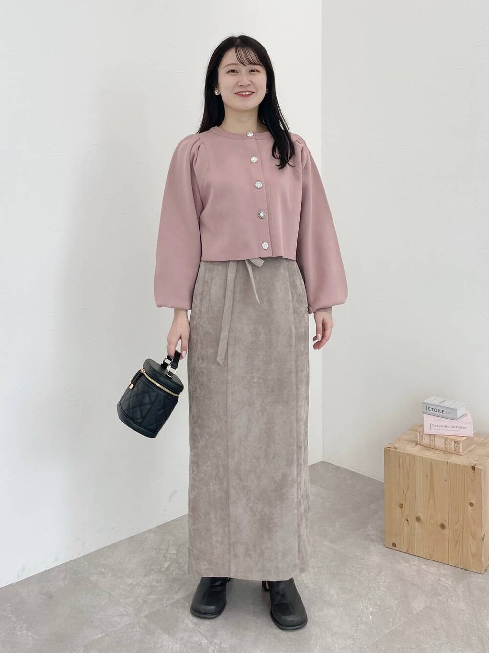 ブラウン系のスカート、ピンク系のカーディガン/ボレロ、グレー系のブーツを着用したレディースの冬コーディネートの1枚目の写真