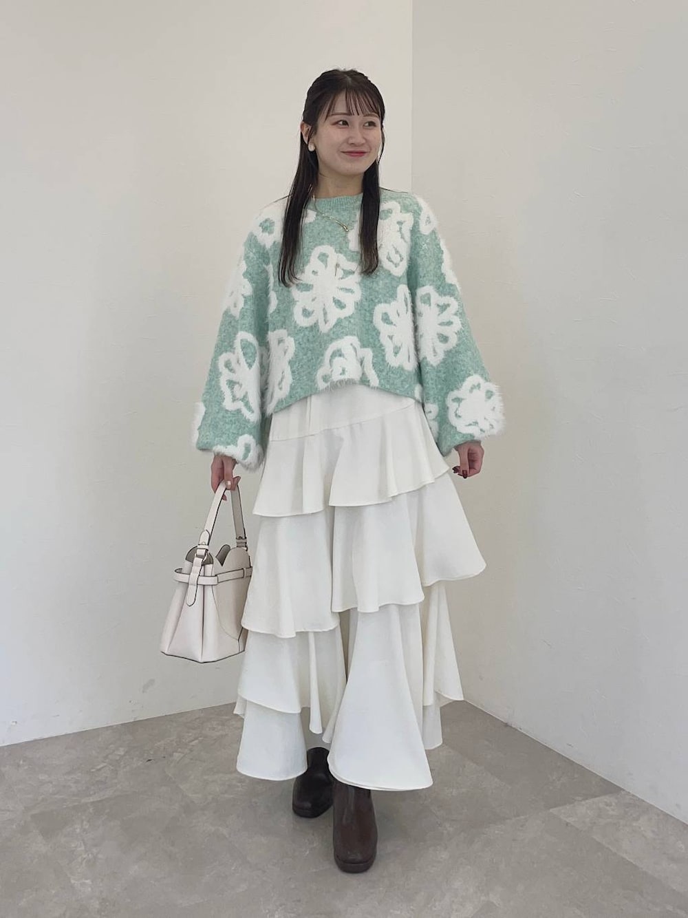 ホワイト系のショルダーバッグ、ブラウン系のブーツ、ホワイト系のスカートを着用したレディースの冬コーディネートの1枚目の写真