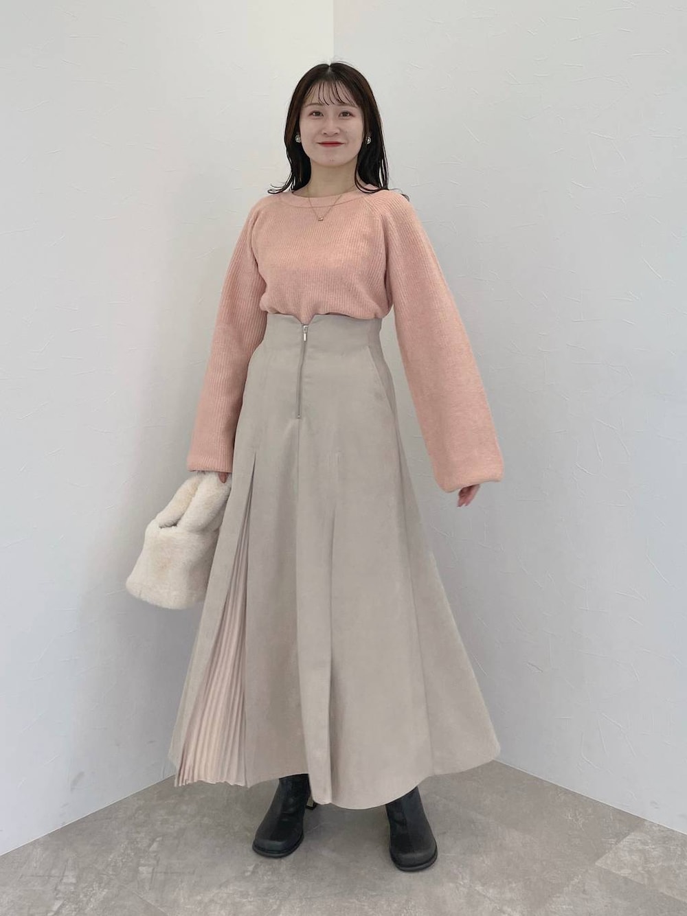 ピンク系のニット/セーター、グレー系のブーツ、ホワイト系のハンドバッグを着用したレディースの冬コーディネートの1枚目の写真