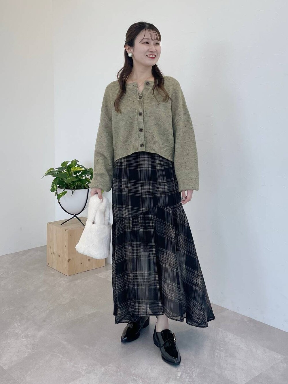 ブラック系のその他シューズ、グリーン系のカーディガン/ボレロ、ブラック系のスカートを着用したレディースの秋コーディネートの1枚目の写真