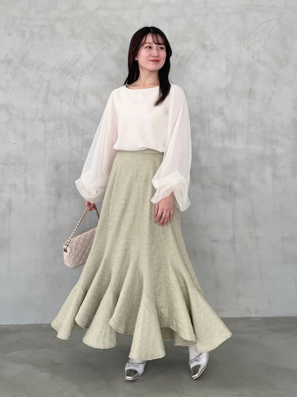 ホワイト系のTシャツ/カットソー、ホワイト系のショルダーバッグ、グリーン系のスカートを着用したレディースの冬コーディネートの1枚目の写真