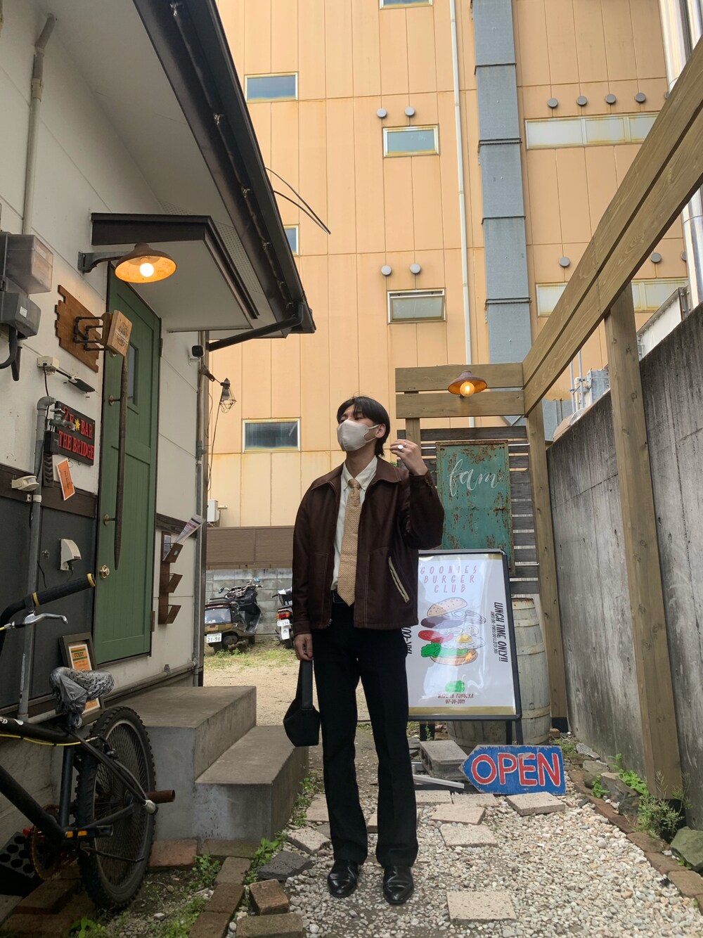 ブラック系のスラックス、ブラック系のドレスシューズ、ブラック系のハンドバッグを着用したメンズの春コーディネートの1枚目の写真