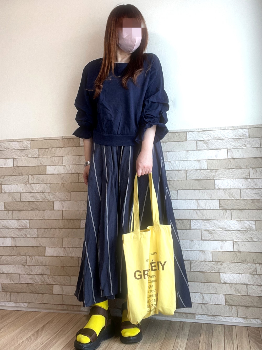 ブルー系のTシャツ/カットソー、イエロー系のトートバッグ、ブラウン系のサンダルを着用したレディースの春コーディネートの1枚目の写真