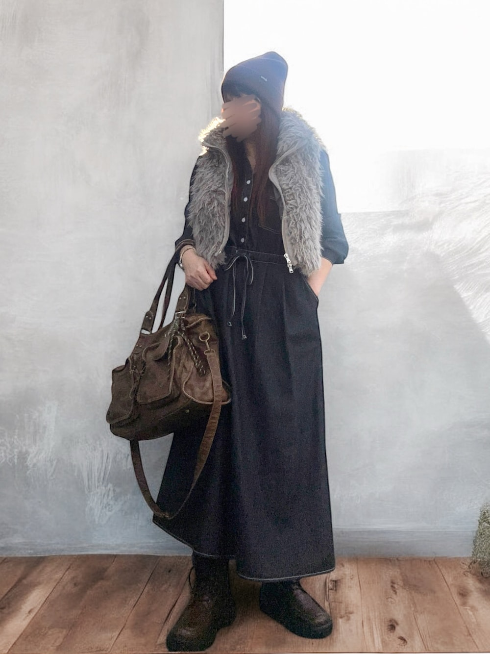 ブラウン系のベスト、ブラック系のワンピース、ブラウン系のバッグを着用したレディースの秋コーディネートの1枚目の写真