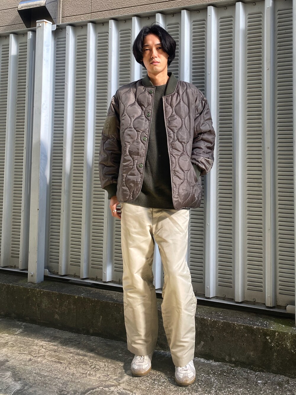 グリーン系のニット/セーター、グリーン系のミリタリージャケット、ベージュ系のパンツを着用したメンズの秋コーディネートの1枚目の写真