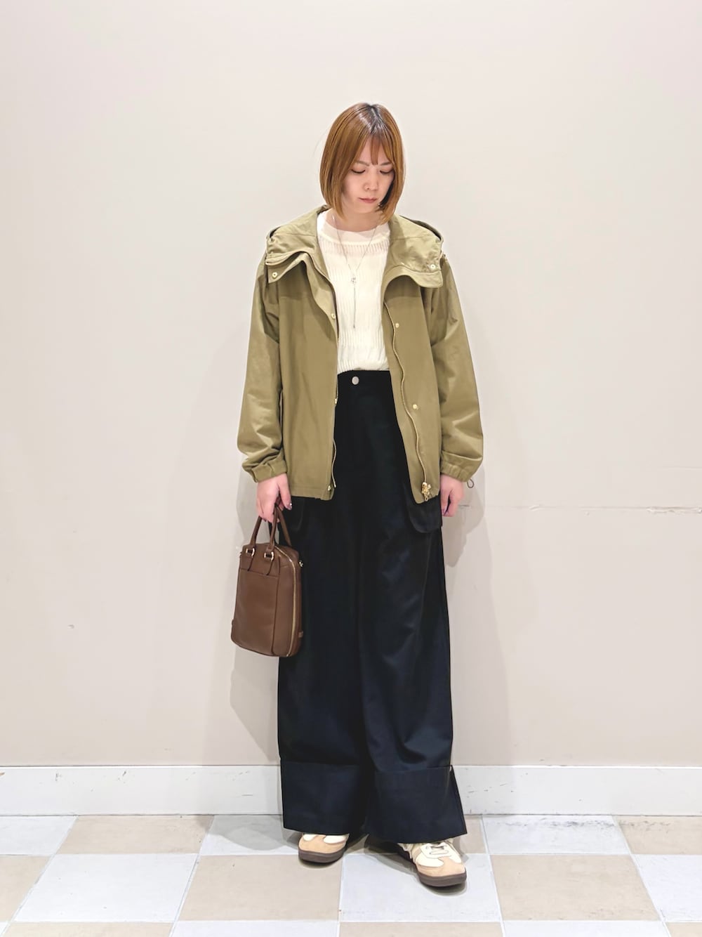 ホワイト系のニット/セーター、ブラック系のその他パンツ、ベージュ系のマウンテンパーカーを着用したレディースの春コーディネートの1枚目の写真