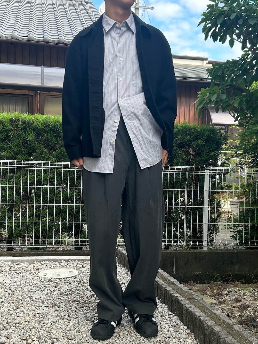 ブラック系のスニーカー、グレー系のシャツ/ブラウス、ブラック系のデニムジャケットを着用したメンズの秋コーディネートの1枚目の写真