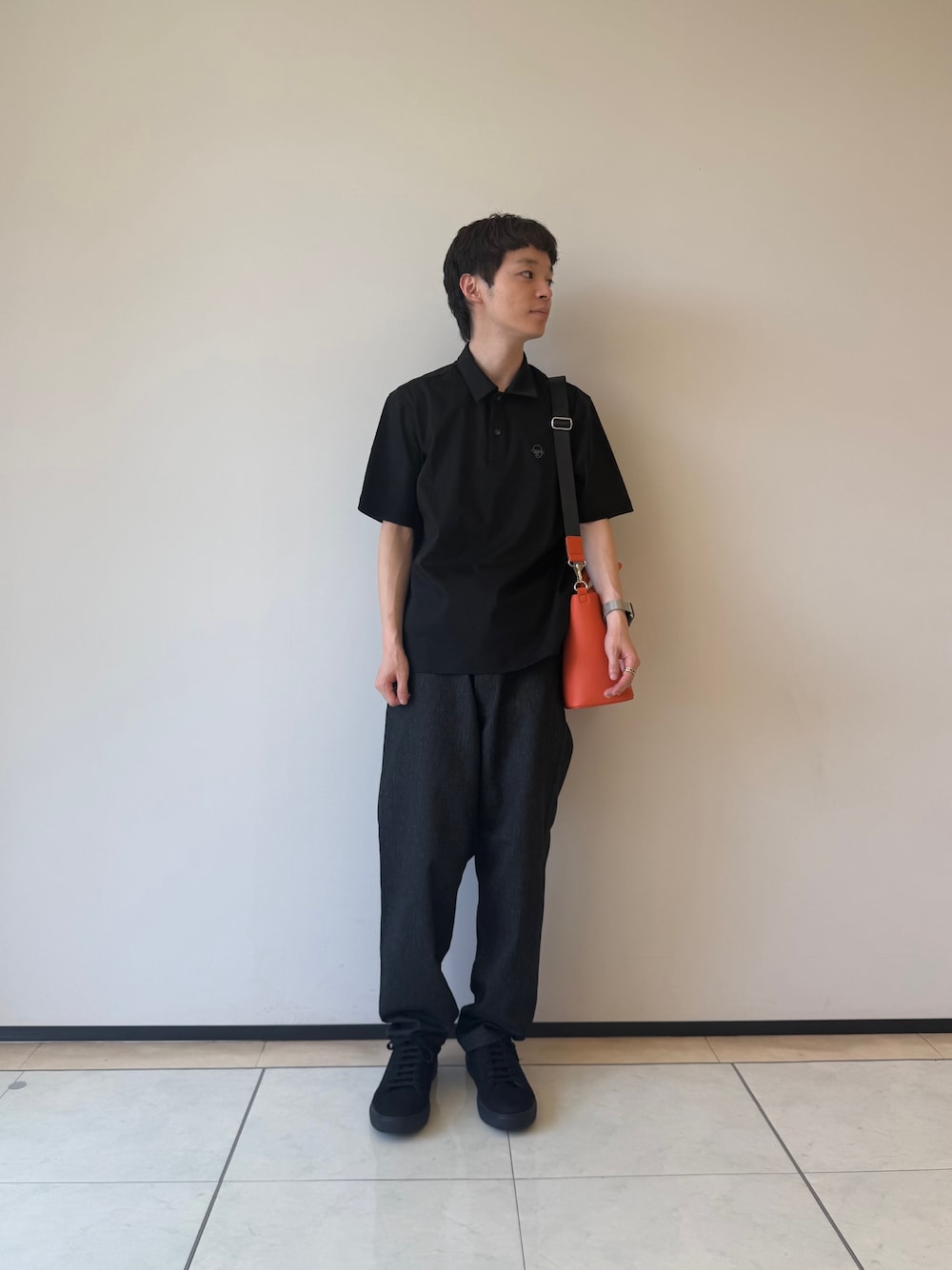 ブラック系のポロシャツ、ブラック系のデニムパンツ、ブラック系のスニーカーを着用したメンズの夏コーディネートの1枚目の写真