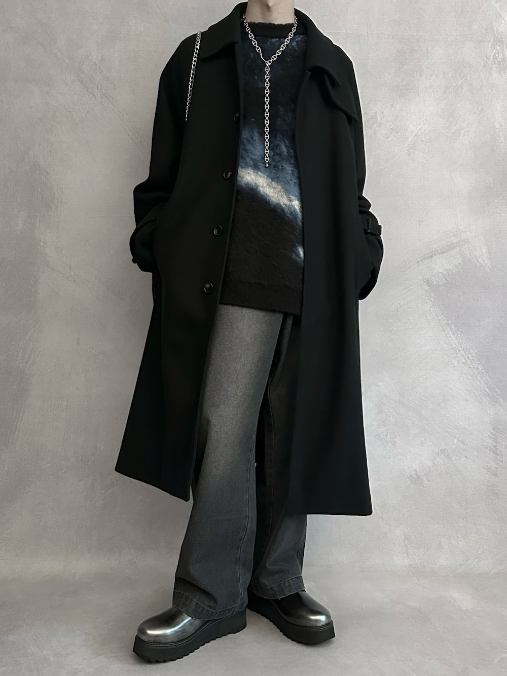 ブルー系のニット/セーター、ブラウン系のデニムパンツ、ブラック系のショルダーバッグを着用したメンズの秋コーディネートの1枚目の写真