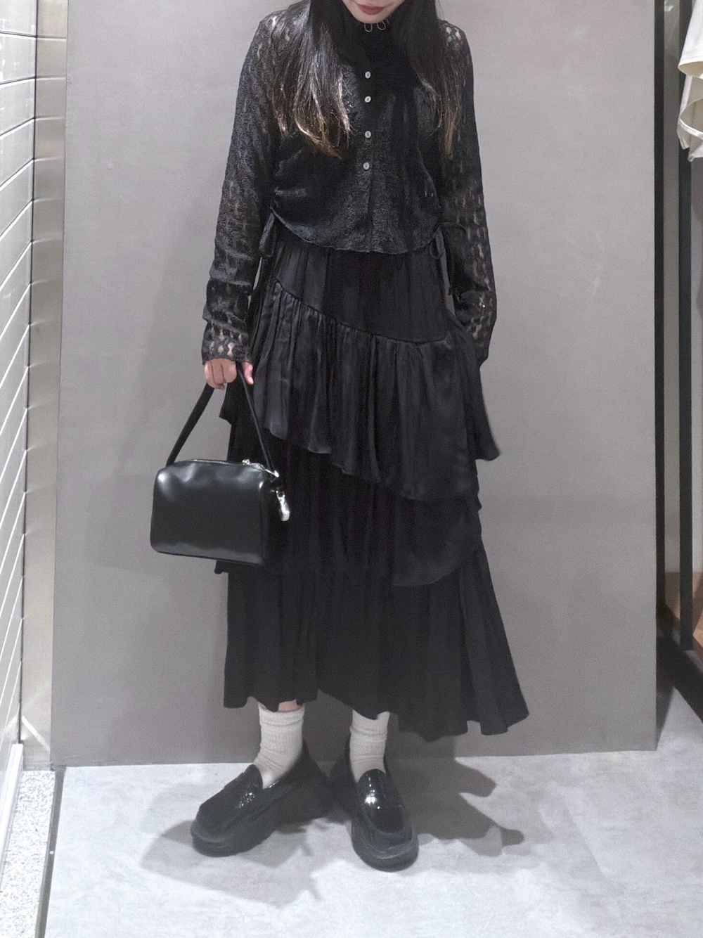 ブラック系のTシャツ/カットソー、ブラック系のスカート、ブラック系のハンドバッグを着用したレディースの春コーディネートの1枚目の写真
