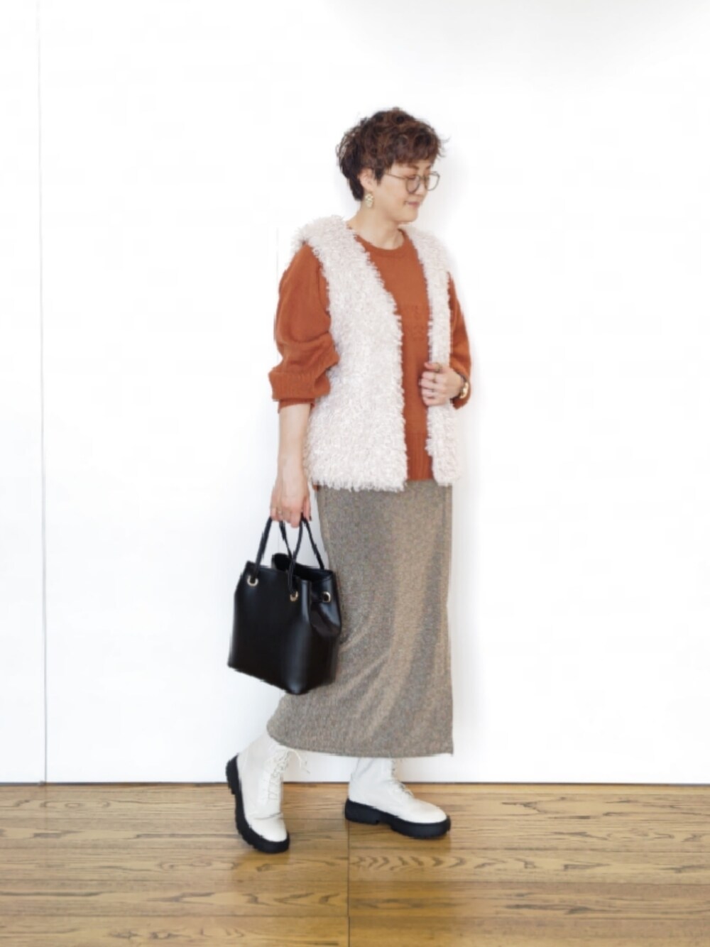 ホワイト系のベスト、オレンジ系のニット/セーター、ベージュ系のスカートを着用したレディースの秋コーディネートの1枚目の写真