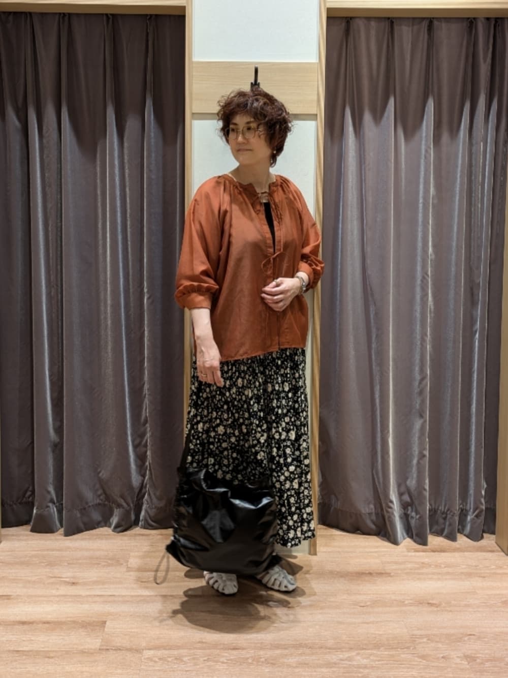 オレンジ系のシャツ/ブラウス、ブラック系のスカート、ブラック系のハンドバッグを着用したレディースの夏コーディネートの1枚目の写真