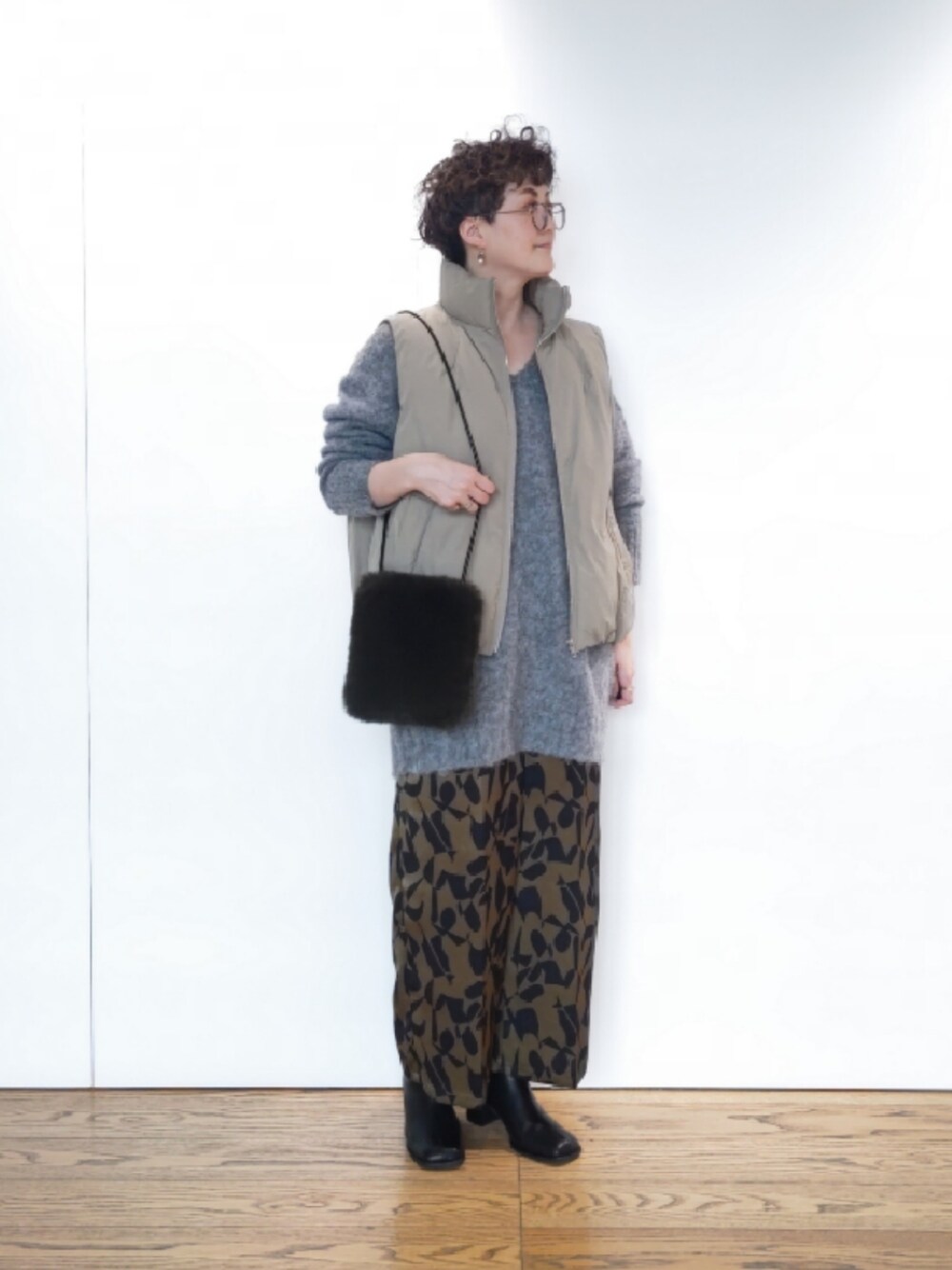 グリーン系のハンドバッグ、グレー系のニット/セーター、ブラック系のブーツを着用したレディースの冬コーディネートの1枚目の写真