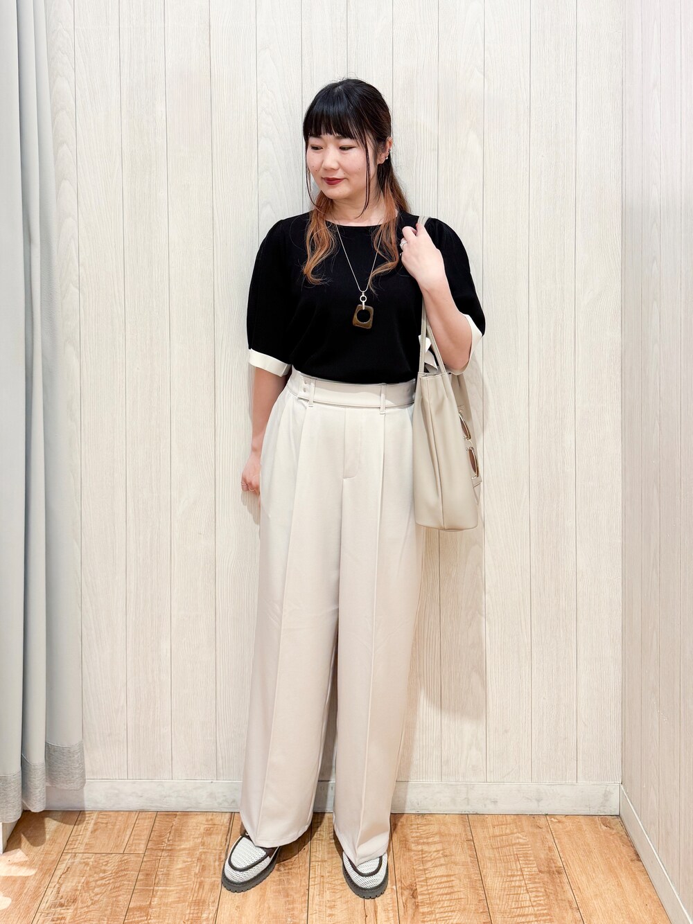 ブラック系のニット/セーター、ベージュ系のその他パンツ、ブラウン系のパンプスを着用したレディースの春コーディネートの1枚目の写真