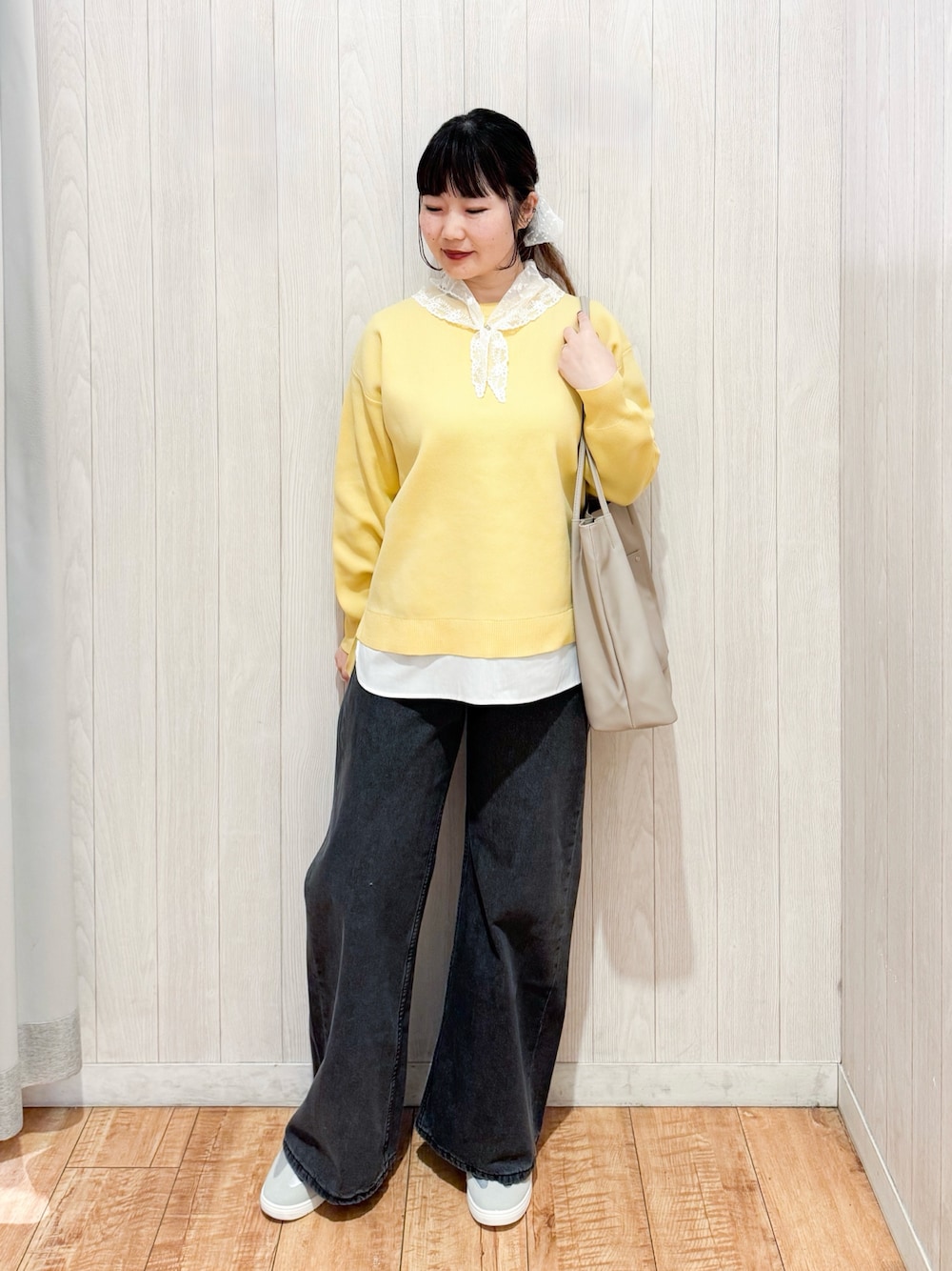 イエロー系のニット/セーター、ブラック系のデニムパンツ、シルバー系のスニーカーを着用したレディースの冬コーディネートの1枚目の写真