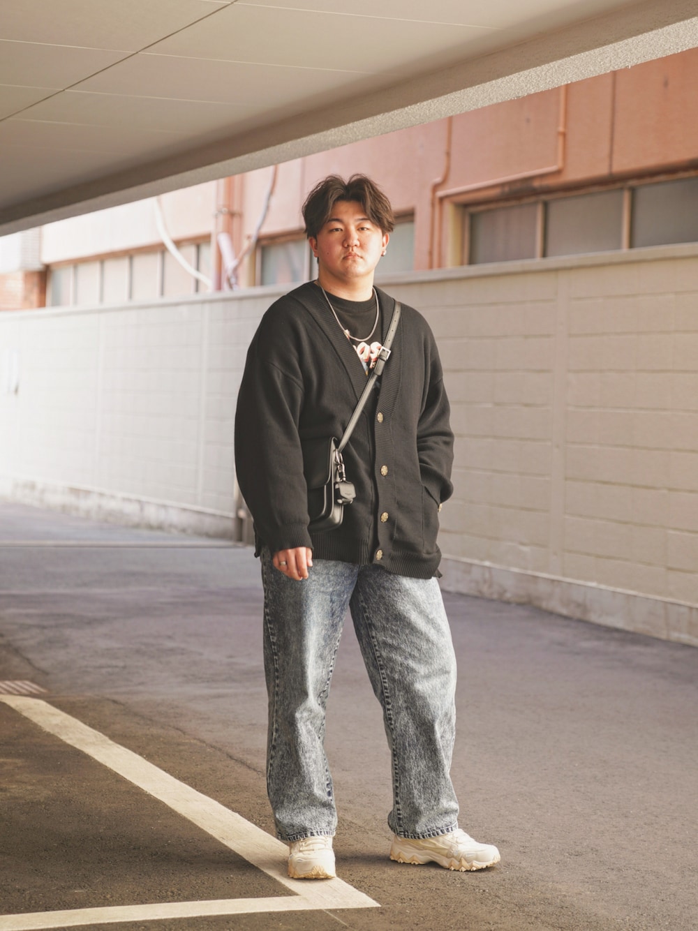 ブルー系のデニムパンツ、ベージュ系のスニーカー、ブラック系のカーディガン/ボレロを着用したメンズの春コーディネートの1枚目の写真