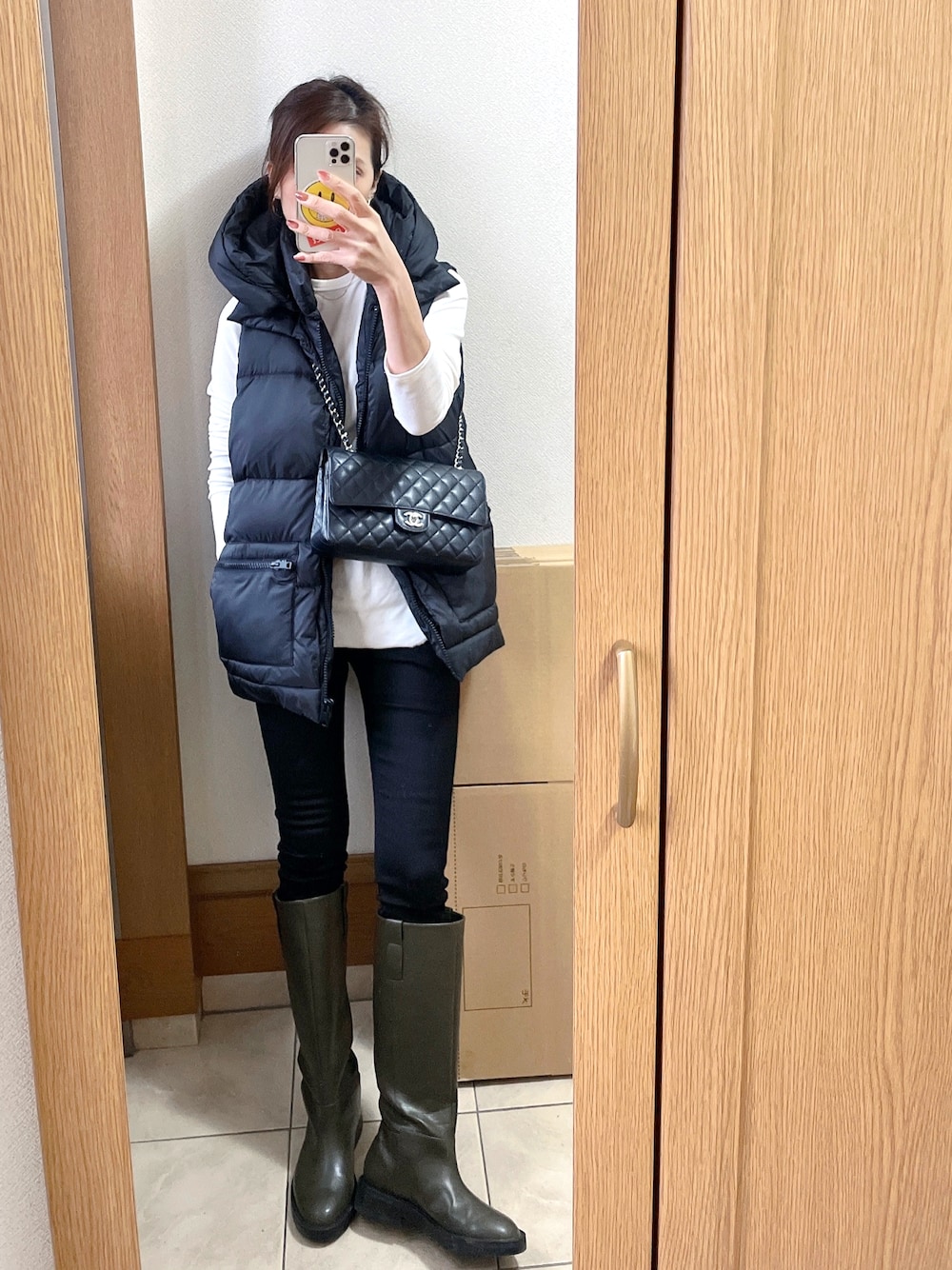 グリーン系のブーツ、ブラック系のパンツ、ブラック系のダウンベストを着用したレディースの秋コーディネートの1枚目の写真