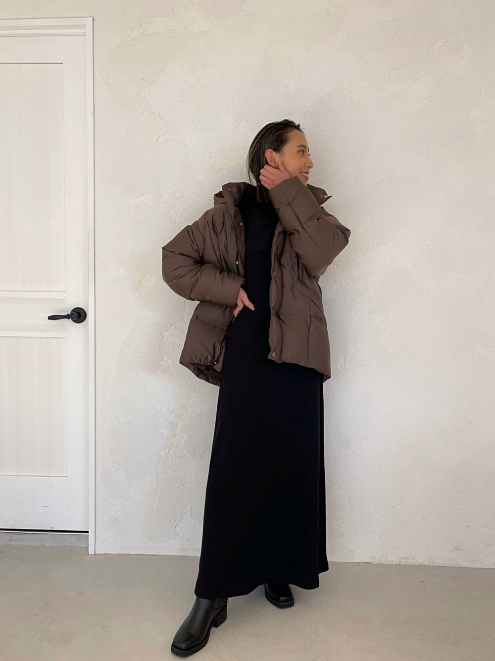 ブラック系のワンピース、ブラック系のブーツ、ブラウン系のダウンジャケット/コートを着用したレディースの冬コーディネートの1枚目の写真
