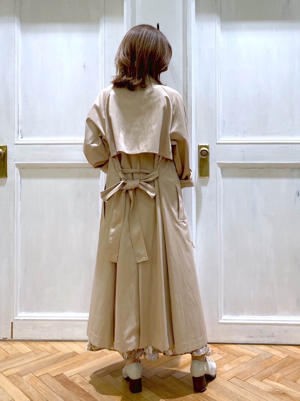 ベージュ系のトレンチコート、ベージュ系のニット/セーター、ホワイト系のスカートを着用したレディースの春コーディネートの4枚目の写真