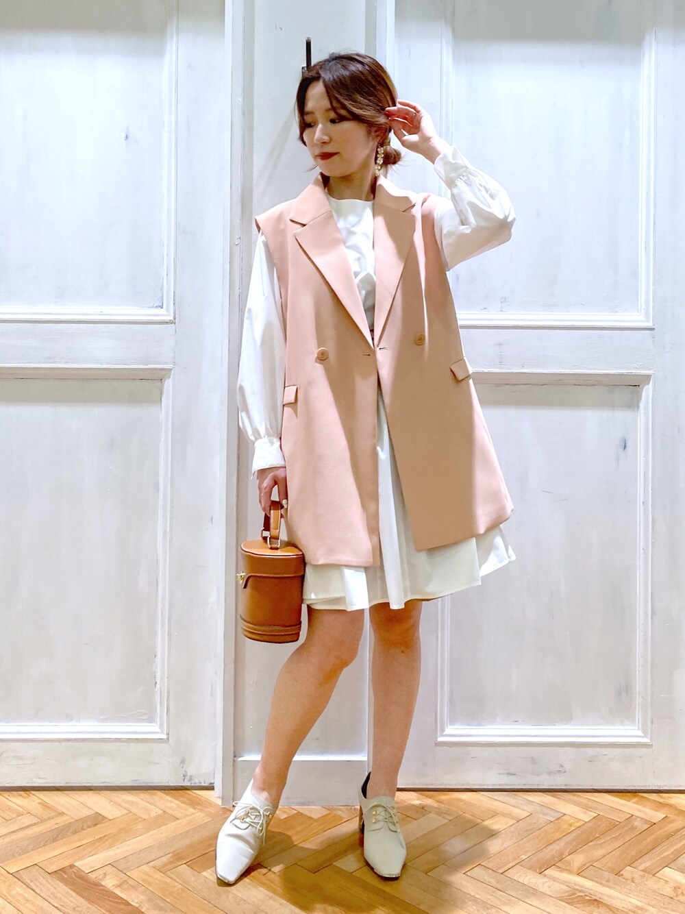 ピンク系のテーラードジャケット、ホワイト系のトップス、ブラウン系のショルダーバッグを着用したレディースの春コーディネートの2枚目の写真